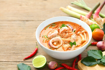 Tom yum soup with ingredient seasoning on wooden table.