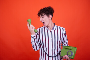 Young attractive emotional guy posing in the studio on an orange background.