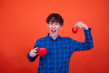 Young attractive emotional guy posing in the studio on an orange background.