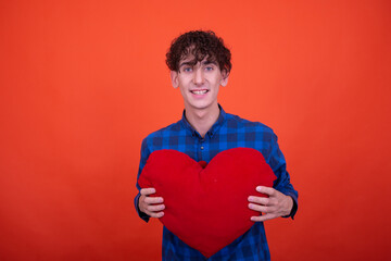 Young attractive emotional guy posing in the studio on an orange background.