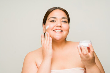 Cheerful fat woman using anti aging moisturizing cream