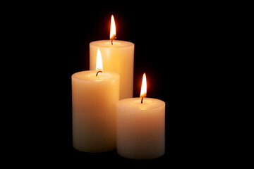 Fototapeta na wymiar White candles burning on black background.