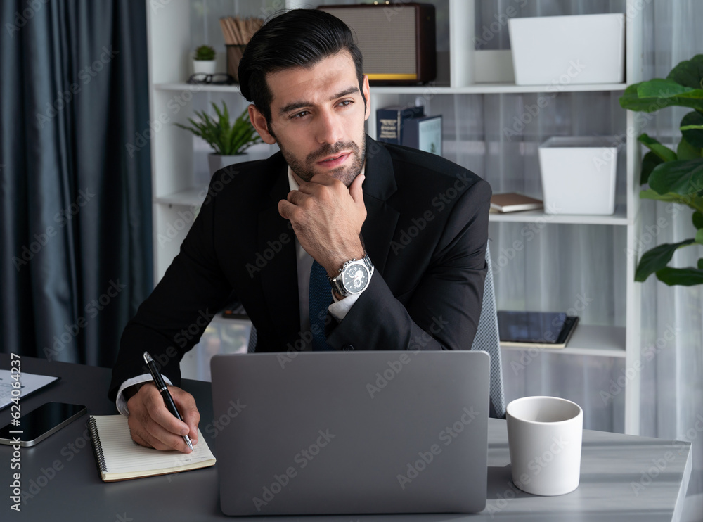 Poster modern professional businessman at modern office desk using laptop to work and write notes. diligent