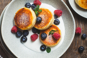Cottage cheese pancakes with creamy sauce, raspberries and blueberries