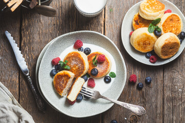 Fototapeta na wymiar Cottage cheese pancakes with creamy sauce, raspberries and blueberries