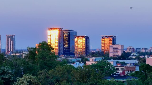 Aerial view of Bucharest city at sunset. One tower and TVR National Romanian Television building in the frame. Cityscape with business center towers. Sun reflection in the glass of skyscrapers tower. 