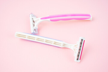 The Two plastic, disposable razors on pink color background.