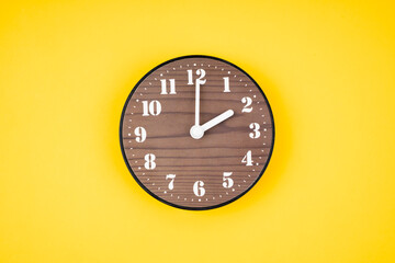 The Retro wooden clock at 2 O' clock on yellow color background.