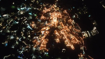 Cinematic 4k aerial video of the Greek town of Pyrgos being illuminated by rooftop candles during orthodox easter good friday celebrations on the island of Santorini