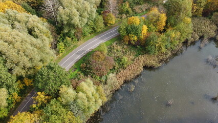 Jesienne zdjęcie parku z drona na którym widać drzewa, jezioro i drogę rowerową / Autumn photo of the park from a drone showing trees, a lake and a bicycle path