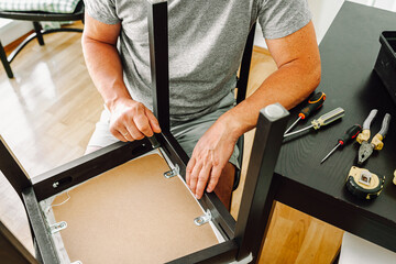 Middle aged man handyman fixing chair at home
