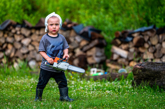 Funny picture of a young boy with a diaper on his head holding a toy chainsaw.