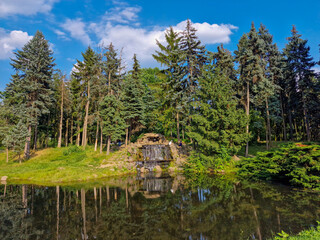 Obraz premium Landscape with cascading waterfall in scenic natural park. waterfall ond lake in the coniferous forest