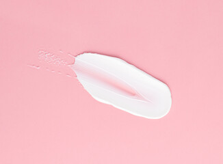 Smear of white cream for face and body on a pink background