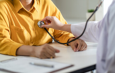 Doctor using a stethoscope checking patient stethoscope putting beat heart diagnose medical checkup cardiologist in examination room.