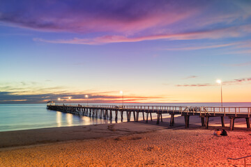 Henley Beach jetty at dusk with the tranquil sea embracing the weathered pillars with purple cluds...