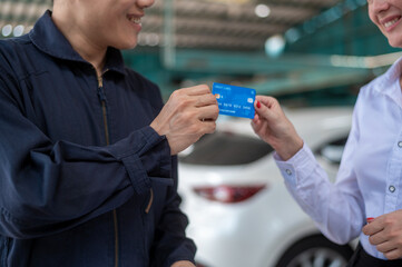 A young Caucasian woman paying via credit card to mechanic man in repair service shop