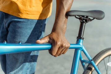 Closeup portrait of African American man holding bicycle on urban street selective focus on hand