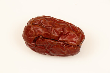 Dried jujube seeds which are brown overlay on a white background. Jujube seeds is an ingredient in desserts, soups and drinks. Close-up 