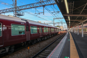 Fototapeta na wymiar Moving Hankyu Local Train in city in Osaka with blue sky background
