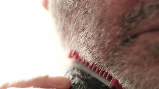 Close-up of clipper trimming beard.