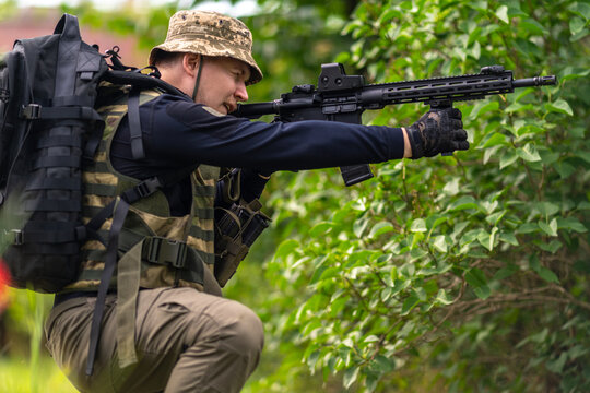 A man in military uniform aims a rifle
