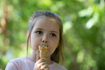 Summer portrait of a girl of seven years old who eats ice cream in a waffle cup