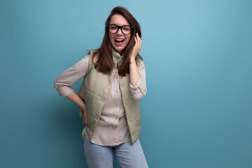emotional young brunette woman with poor eyesight wears glasses on studio background with copy space