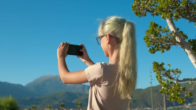 Teen takes photo of tropical vacation. A young girl pass her vacation on tropics and takes photo of sunny nature in summer.