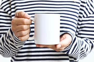 Girl is holding white 11 oz mug in hands . Blank 11 oz ceramic cup