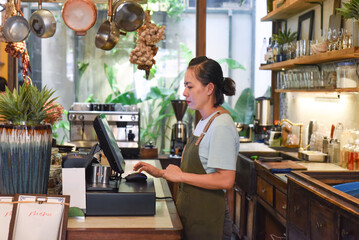 Young Vietnamese waitress working with check out machine in cafe 