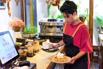Vietnamese young waitress serving sweet waffles with banana and cream in a cafe