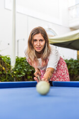 Young blond woman playing billiards in the backyard