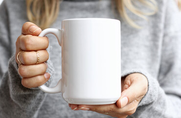 Girl is holding white mug in hands. Blank 15 oz ceramic cup