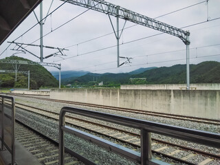Perspective view of empty train tracks and platform of Cheongpyeong station with mountains and sky background.
