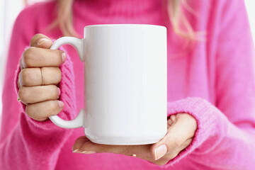 Girl is holding white 15 oz mug in hands with pink sweater. Blank ceramic cup