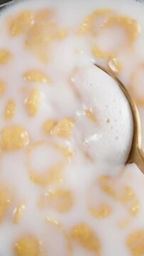 Plate of milk with wheat flakes, eat with a spoon. olly slider close up. Slow motion Vertical video.