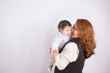 Beautiful photo of loving mom with baby on light photo studio background. Family and baby concept.