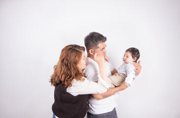 Beautiful photo of Dad and mom being affectionate with baby on light photo studio background. Family and baby concept.