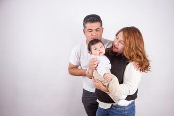 Beautiful photo of Dad and mom being affectionate with baby on light photo studio background. Family and baby concept.