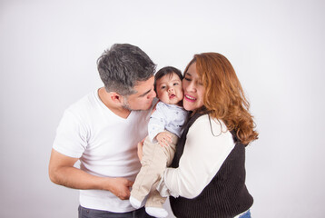 Beautiful photo of Dad and mom being affectionate with baby on light photo studio background. Family and baby concept.