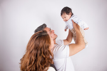 Fototapeta premium Beautiful photo of Dad and mom holding baby on light photo studio background. Family and baby concept.
