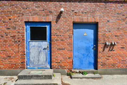old brick wall with two blue doors, industrial building with red stone wall