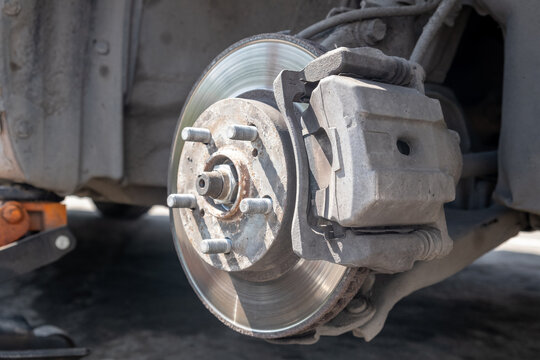Disc brake of the vehicle for repair, in process of new tire replacement. Car brake repairing in garage. Replacement of brake pads. Suspension of car for maintenance brakes and shock absorber systems.