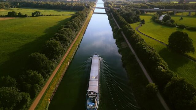 Aerial view of global shipping cargo ship navigating through the inland canal of wesel-datteln, Germany.