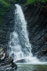 Mountain waterfall, large water flow of mountain waterfall, mountain river near the rock. Huk Waterfall, Ukrainian Carpathians