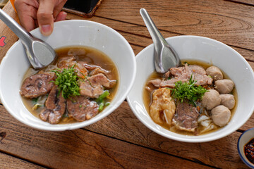 Asian noodle soup with beef meatball with fresh vegetable on wood table vintage style, street food, hot and spicy noodle soup, asian food.