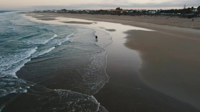 Toma en 4k de drone en playa paradisiaca al amanecer de modelo masculino con ropa urbana