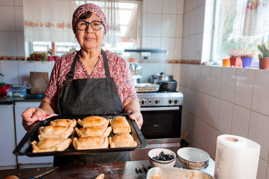 Flavors of Heritage: Latin Elderly Woman Preparing Chilean Baked Beef Empanadas in the Warmth of Her Home Kitchen