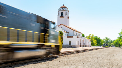 Railroad locomotive speeds past a local train depot